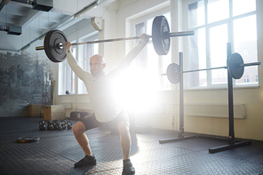 Sportsman squatting while lifting heavy barbell