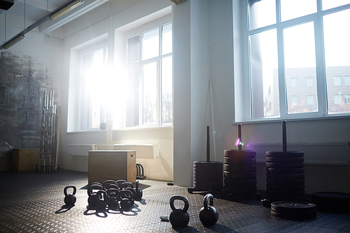 Background image of gym equipment: kettlebells wooden boxes and tire stands in bright sunlight