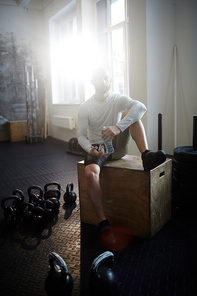 Young sportsman drinking water in gym after training