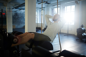 Young sportsman doing sit-ups on sport equipment