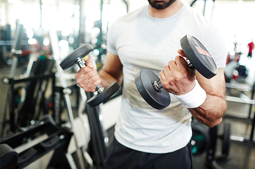 Muscular athlete sweating while pumping biceps