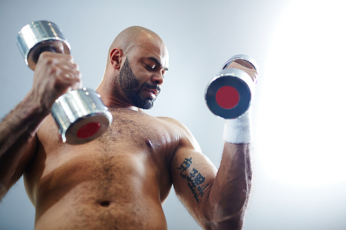 Shirtless man practicing exercise with barbells