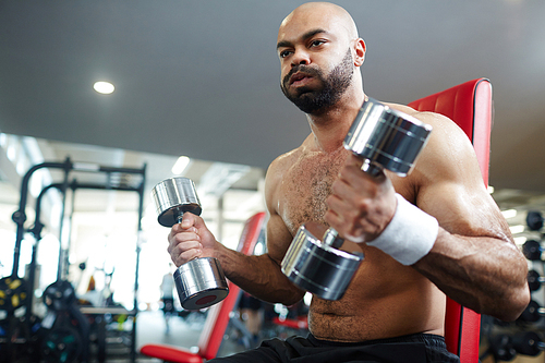 Young man sweating while exercising with dumbbells