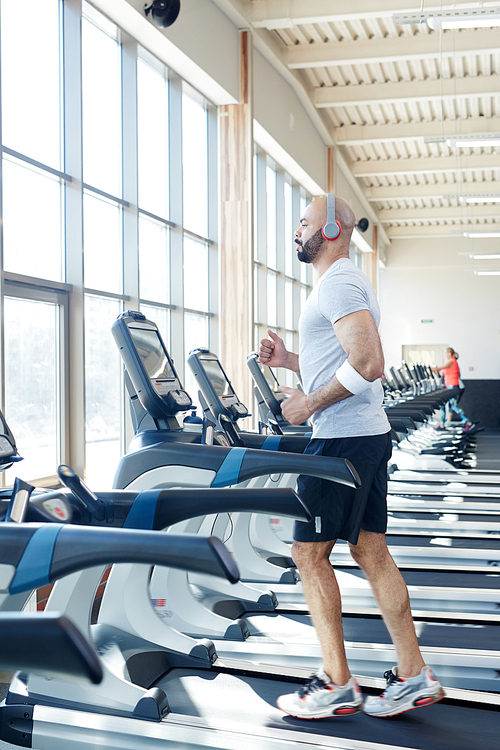 Sporty man walking on treadmill in gym