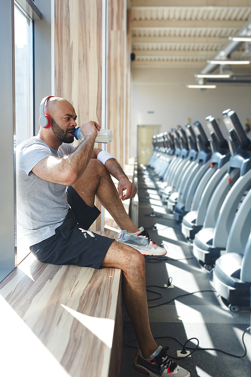 Thirsty man drinking water in gym after training