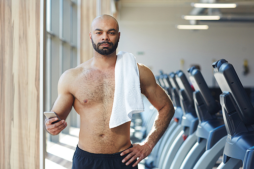 Portrait of handsome shirtless man  confidently after working out in modern gym
