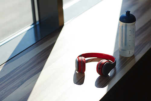 Plastic bottle with water and headphonees on window-sill