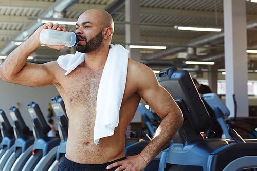 Young athlete drinking water while having rest after training