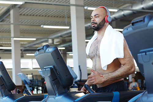 Sporty man jogging on treadmill in gym
