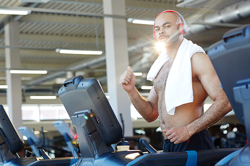 Shirtless man with towel exercising on treadmill in gym