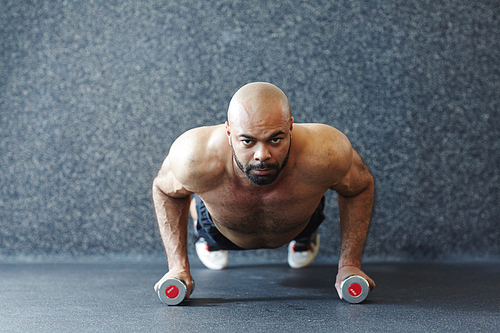 Young man with dumbbells doing planks