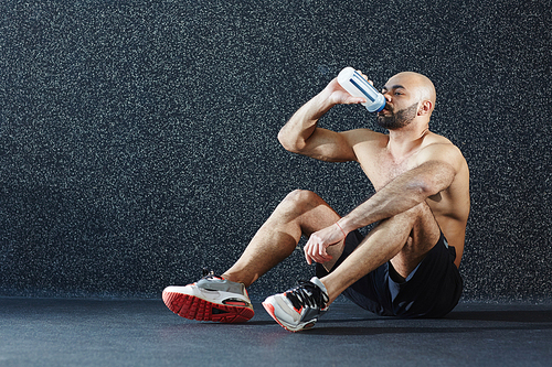 Sporty man drinking water from plastic bottle after workout