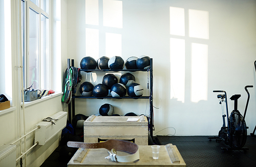 Background image of various equipment in gym: medballs on stand, jumping boxes and exercising machines