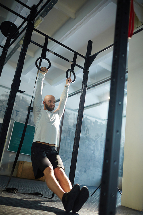 Sportsman keeping balance while training on gymnastic rings