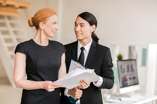 Businesswoman with papers interacting with co-worker in office