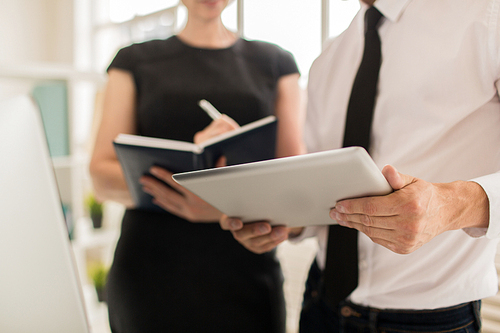 Close-up shot of unrecognizable colleagues analyzing statistic data presented on digital tablet screen while having working meeting at open plan office, blurred background