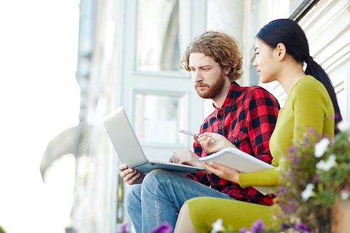 Modern students discussing data in laptop while preparing for seminar or conference