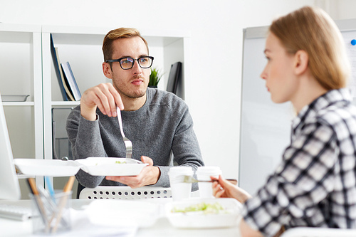 Serious businessman listening to his colleague during lunch break by workplace