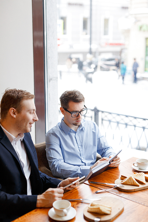 Young specialists discussing financial information at start-up meeting in cafe