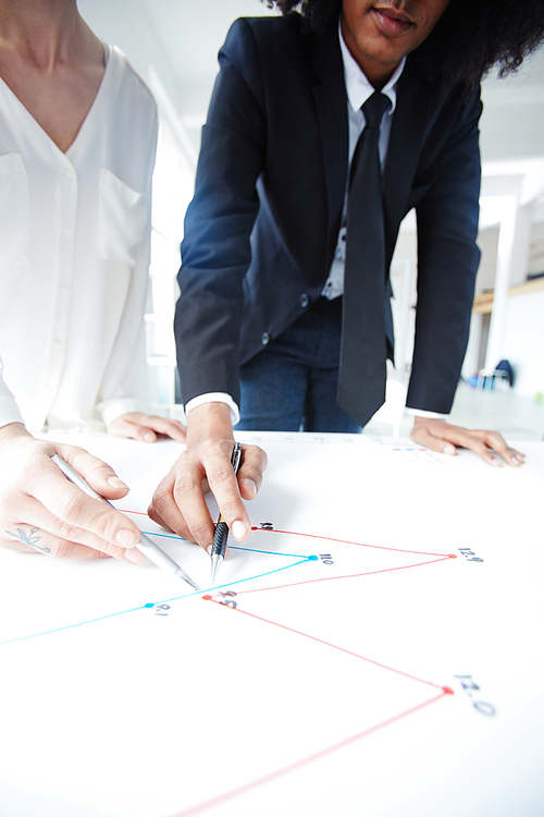 Two professionals pointing at graph on paper while discussing it