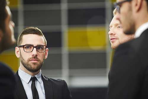 Serious businessman listening attentively to one of colleagues at meeting