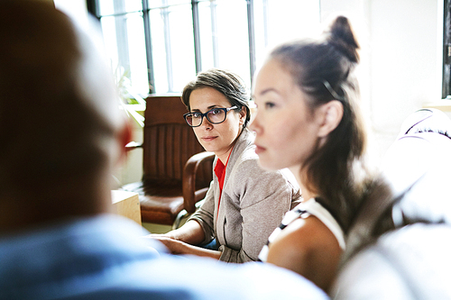 Serious businesswoman listening to opinion of colleague during discussion