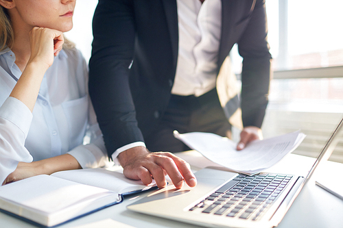 Businessman making online presentation in laptop to his colleague or subordinate by desk