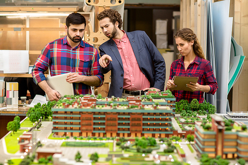 Group of modern architects discussing new layout design of the city at meeting