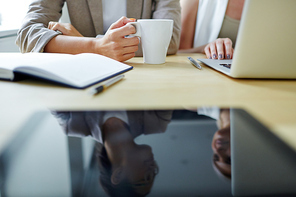 Hands of colleagues having talk by workplace during coffee break