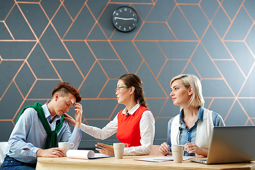 Helpful colleagues supporting and comforting their associate by workplace