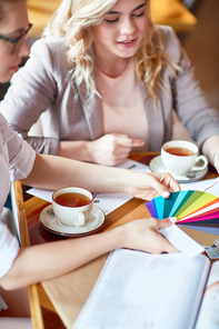 Creative designers of clothes looking at colors in palette by cup of tea