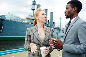 Intercultural co-workers with drinks discussing working plans during business travel