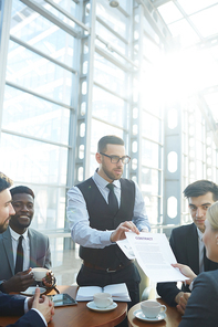 Business leader showing contract to his employees during discussion