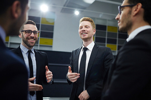 Group of businessmen in suits having discussion of new market trends and tendencies