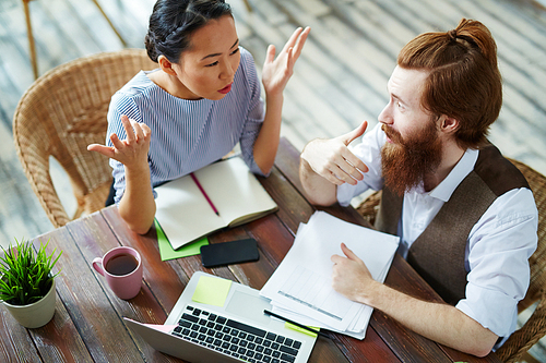 High angle portrait of casual business people arguing, discussing work project emotionally during work meeting in creative studio