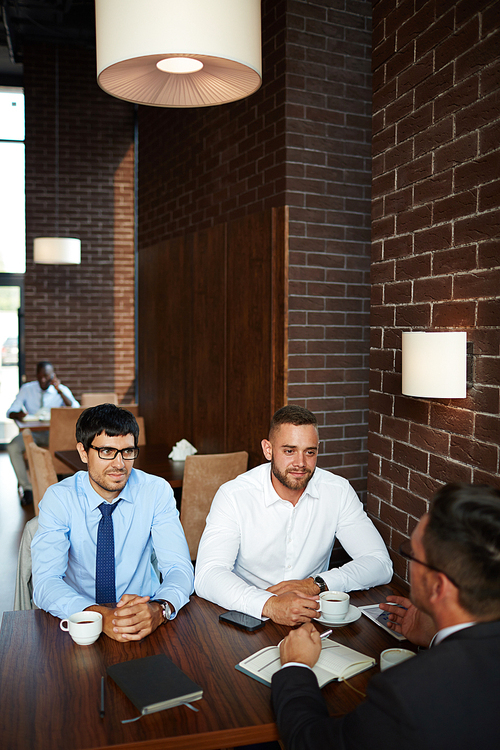 Bearded businessmen having informal meeting at restaurant: they brainstorming on joint project while drinking fragrant coffee