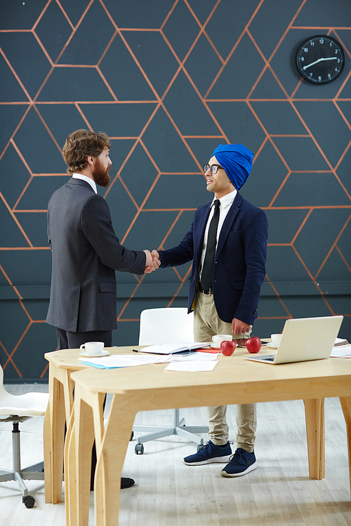 Businessmen handshaking after negotiation by workplace