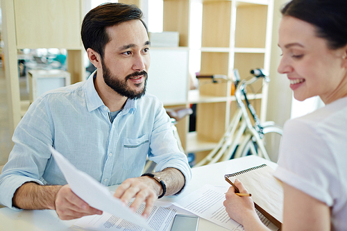 Two young co-workers discussing business papers at meeting