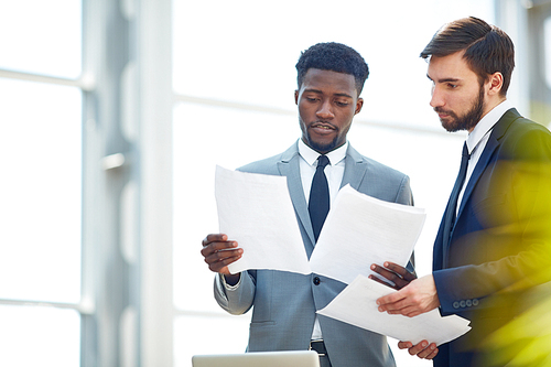 Confident businessmen discussing papers at meeting