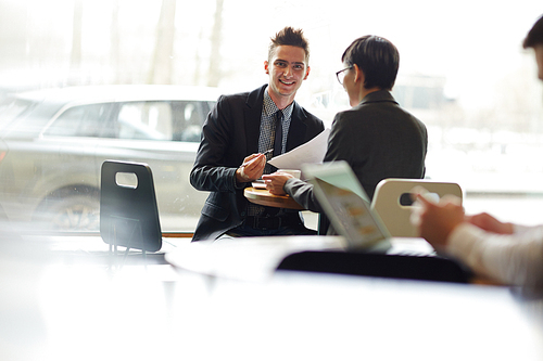 Young successful agent  while consulting client in cafe