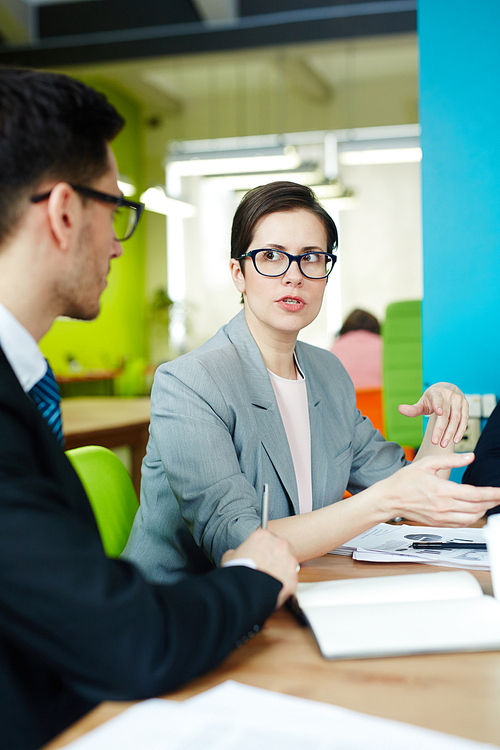 Confident businesswoman talking to one of co-workers by workplace