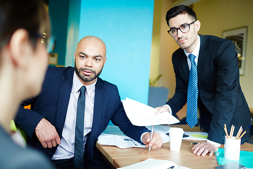 Serious businessmen listening to their colleague at meeting