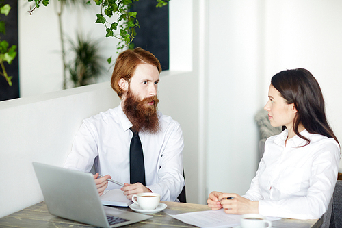 Two young employees having discussion in cafe