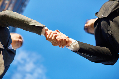Handshake of partners and blue sky above