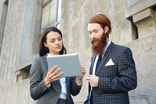 Young economists concentrating on reading online data outdoors