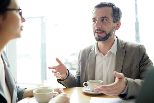 Confident businessman explaining his idea to colleague at coffee-break