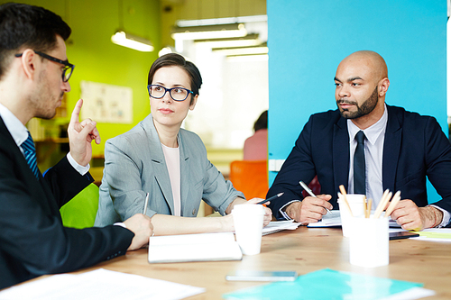 Portrait of three successful business people discussing work in colorful modern office