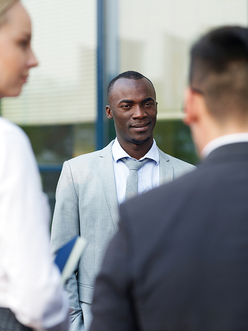 African-american man in formalwear talking to his co-workers