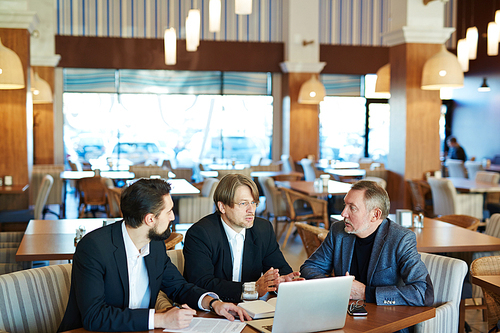 Three men negotiating at meeting in cafe