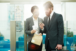 Contemporary office manager sharing mobile app with colleague at break